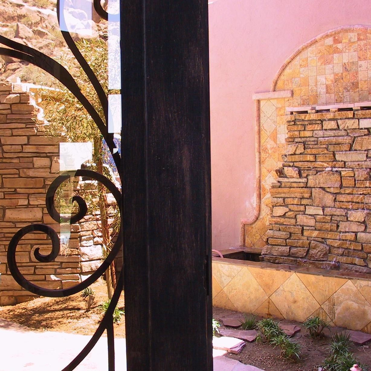 A wrought iron fence with a stone wall in the background