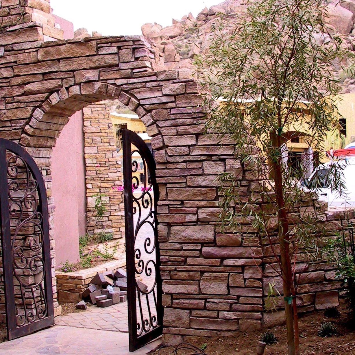 A stone wall with a wrought iron gate in front of it