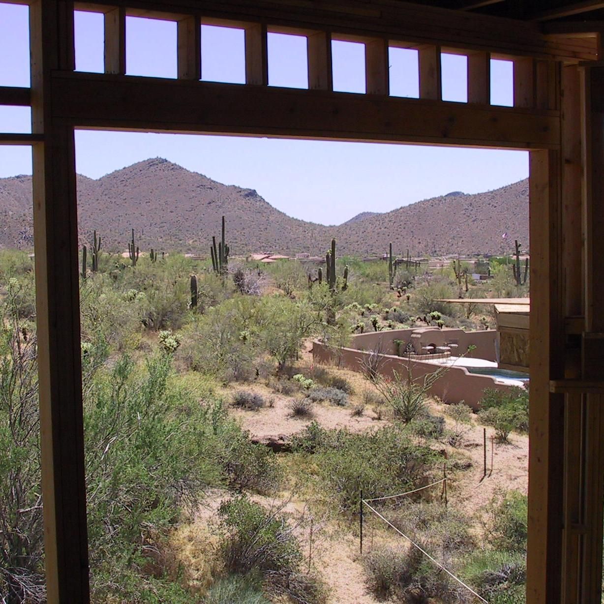A view of the desert through a window with mountains in the background