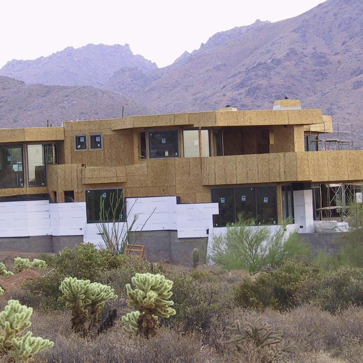 A large house in the desert with mountains in the background