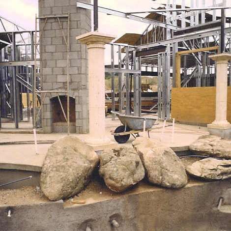 A wheelbarrow is parked in front of a building under construction.