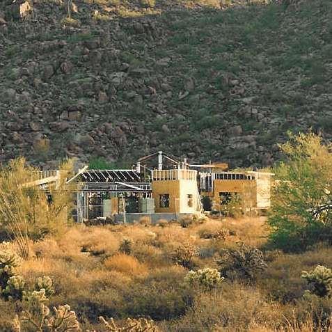 A large house is sitting on top of a hill in the desert.
