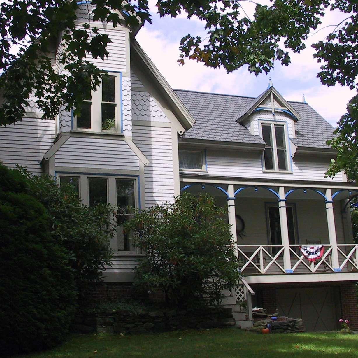 A large white house with a porch and a flag on it