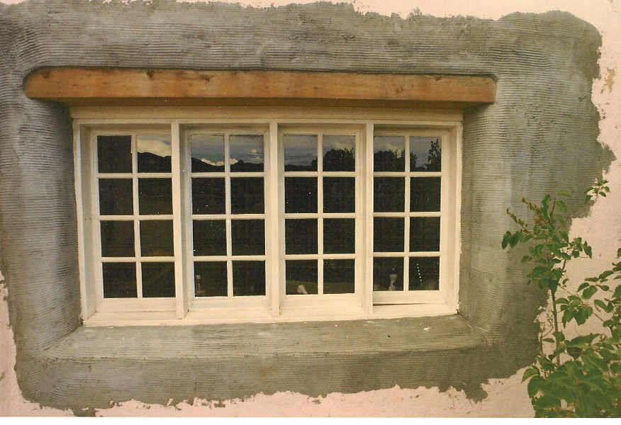 A window with a wooden frame is being built into a wall