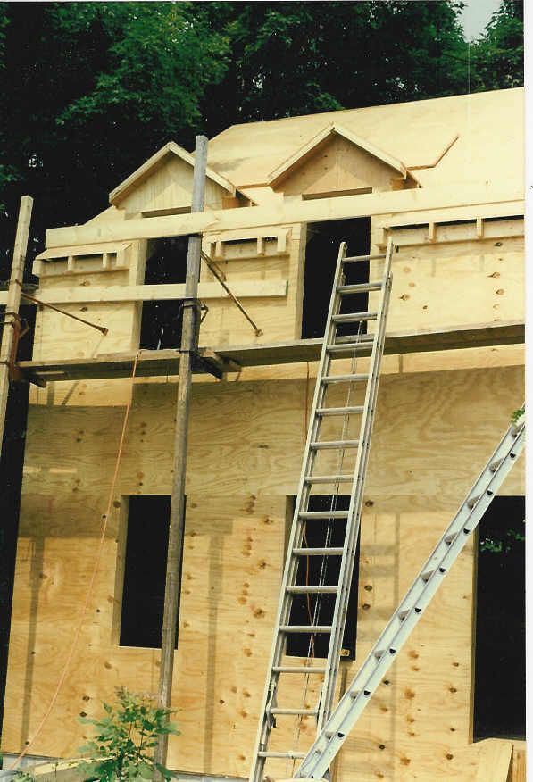 A ladder is leaning against the side of a house under construction