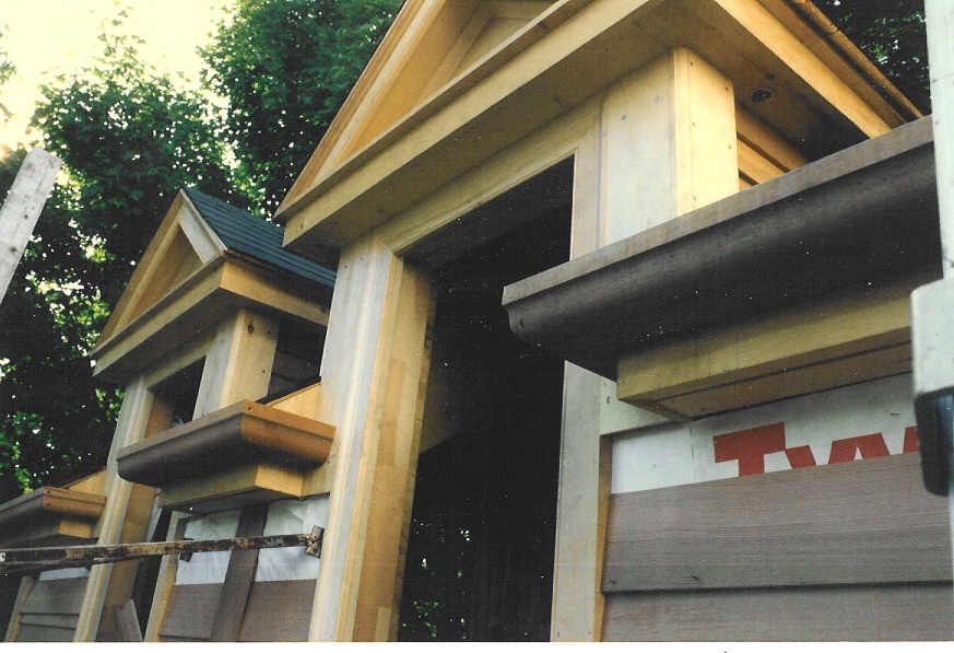 A row of wooden houses are being built and one has a t on it