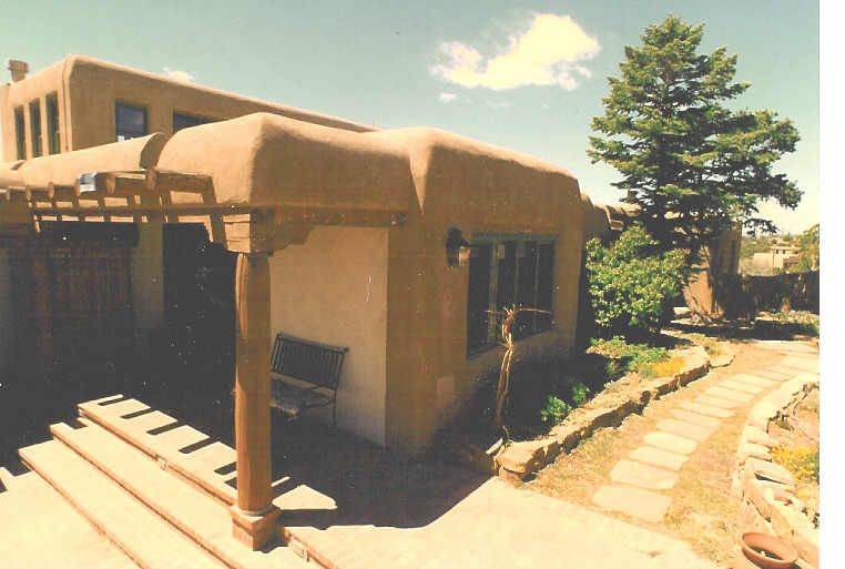 A house with a pergola and a tree in front of it