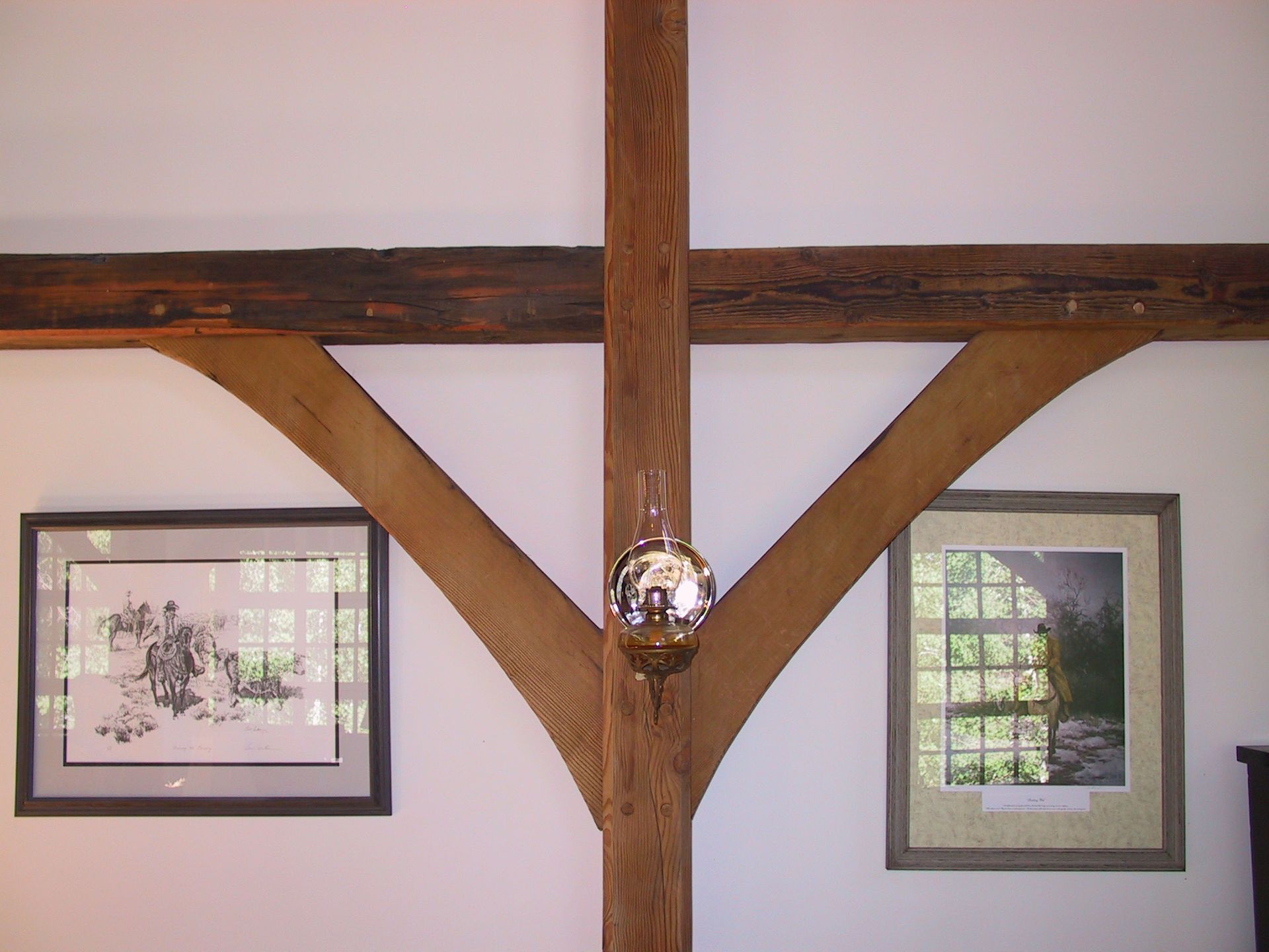 Two framed pictures are hanging on a wall next to a wooden beam