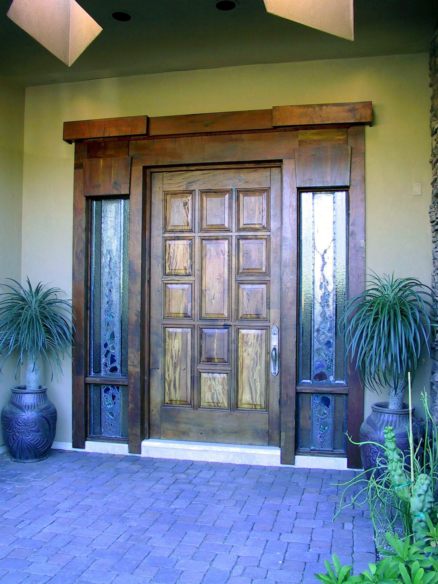 A large wooden door is surrounded by potted plants