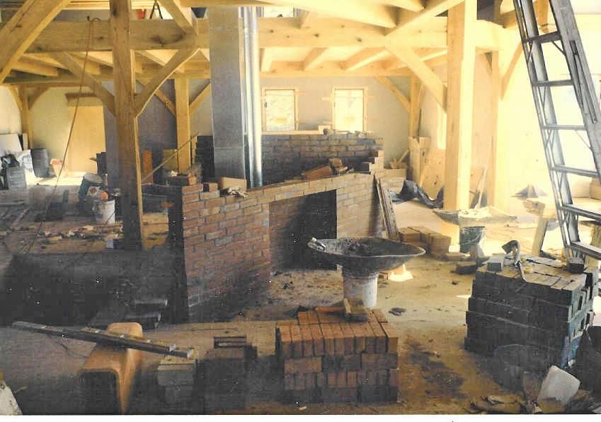 A brick fireplace is being built in a building under construction