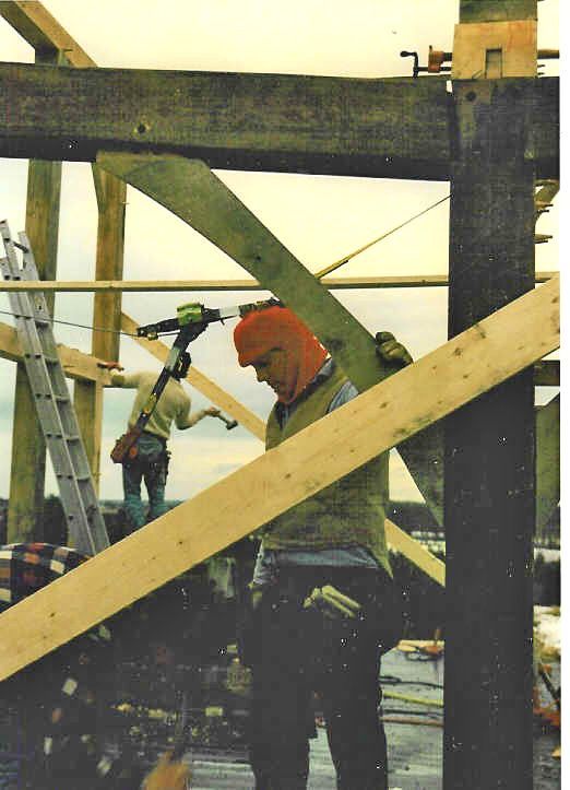 A man wearing a red hat is working on a wooden structure