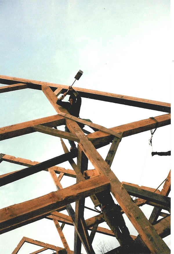A man is working on a wooden structure with a hammer
