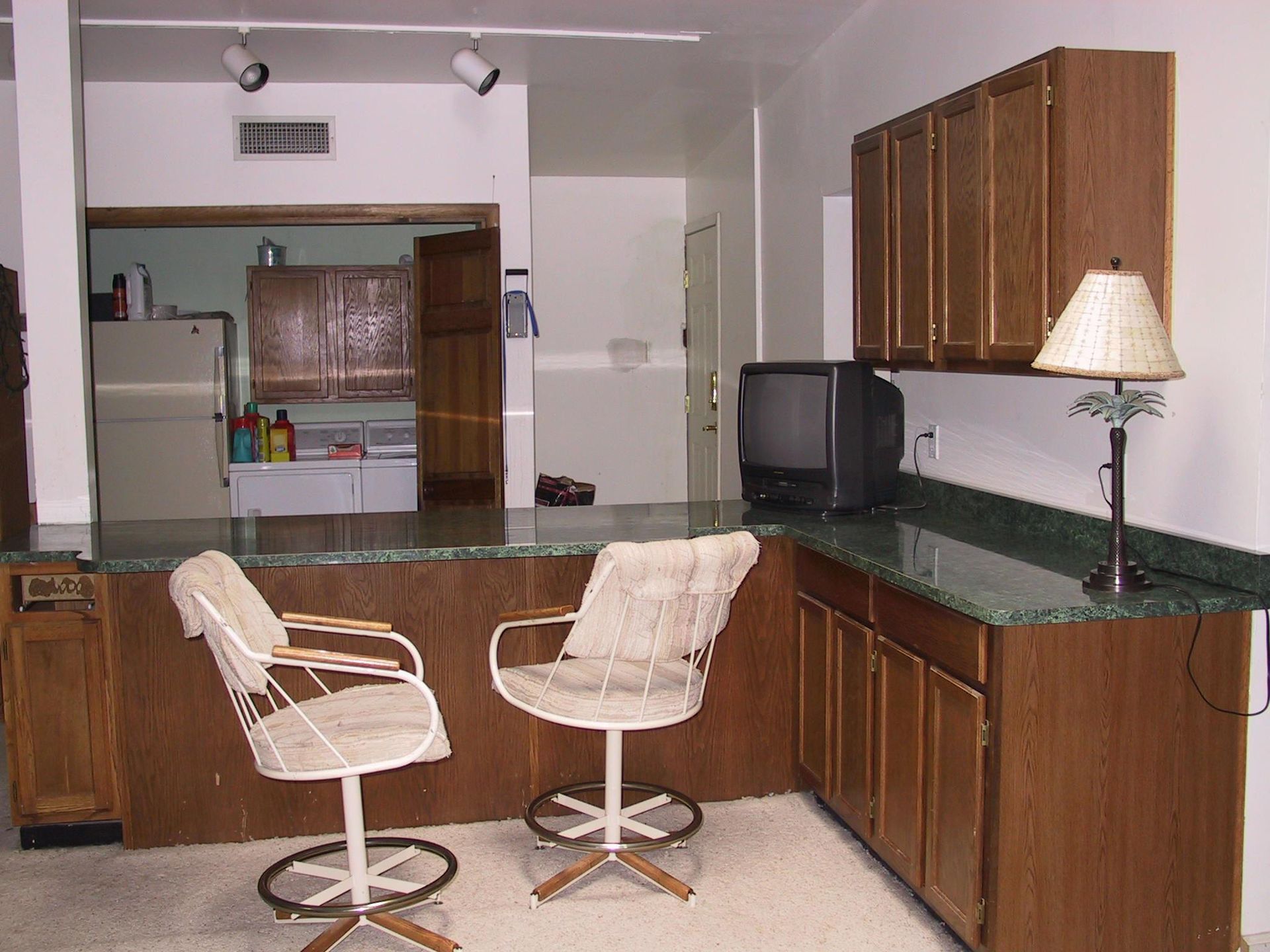 A kitchen with two chairs and a tv on the counter
