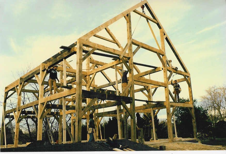 A large wooden structure is being built in a field