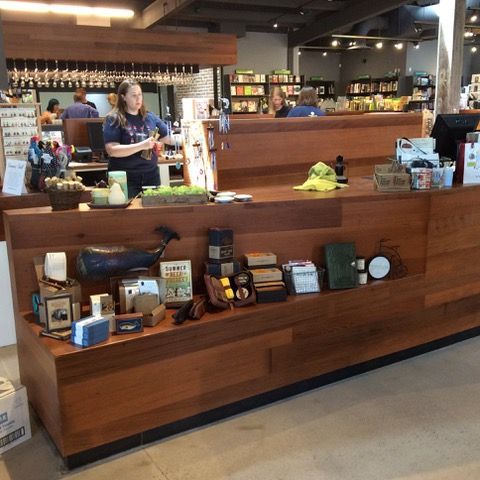 A store counter with merchandise on display; a woman stands behind the counter.