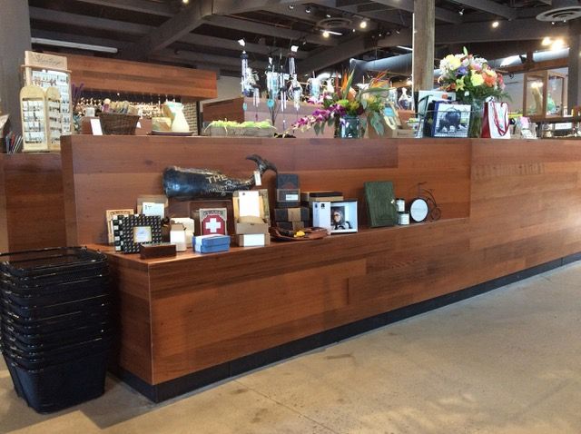 Wooden store counter with various items displayed, including gifts and a stack of shopping baskets.