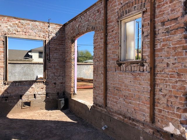 Interior of a brick building with window and doorway openings; sunlit.
