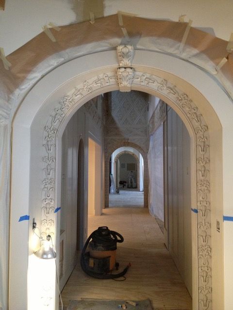 A hallway with arched doorways being renovated; a vacuum cleaner sits in the foreground.