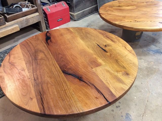 Two round wooden tables with warm wood grain in a workshop.