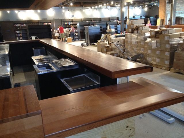 Wooden bar under construction in a spacious interior. Boxes and workers in background.