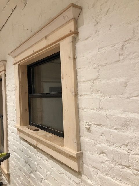 Window with light wood trim on a white painted brick wall.
