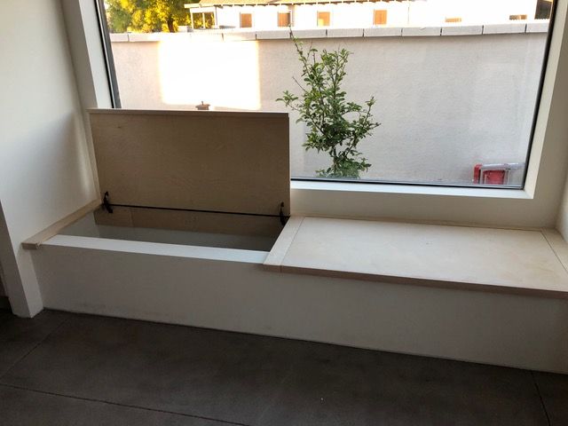White window seat with an open storage compartment and a closed flat surface, built into the window frame.