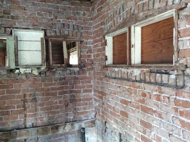 Brick interior with boarded-up windows and an open window frame.