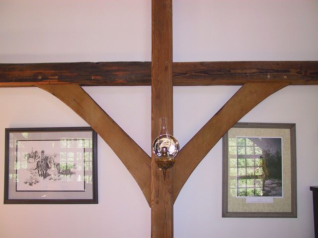 Wooden beam structure with art on white wall; silver sphere hanging.