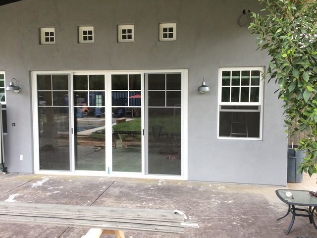 Gray house exterior with sliding glass doors, small window, and outdoor patio furniture.