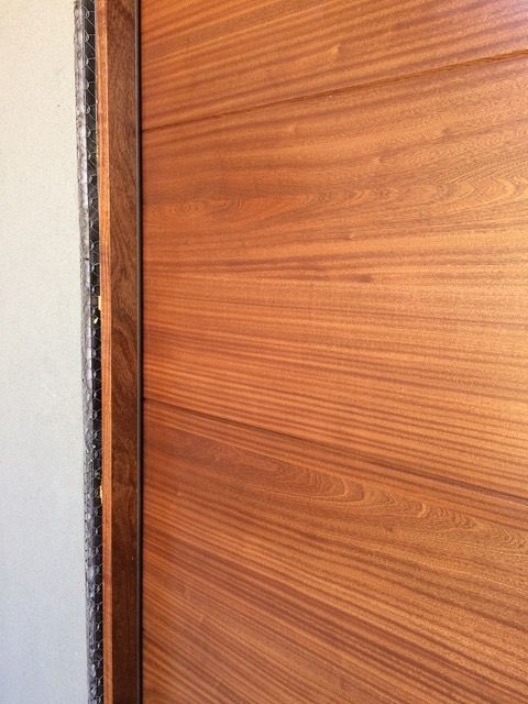 Wooden door with horizontal wood grain, next to a white wall and dark trim.