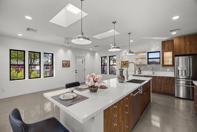Modern kitchen with white island, stainless steel appliances, and wood cabinets.