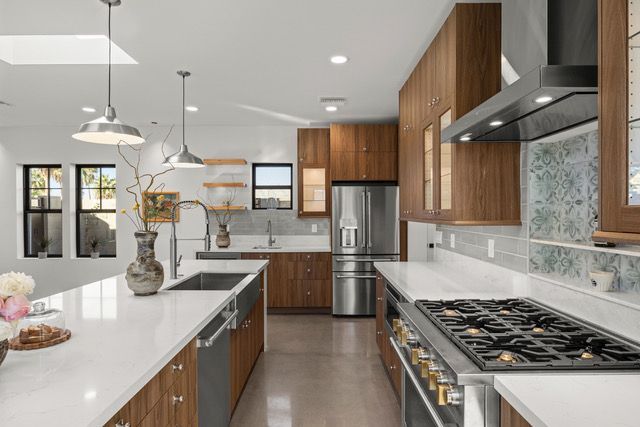 Modern kitchen with white countertops, stainless steel appliances, and wood cabinets.