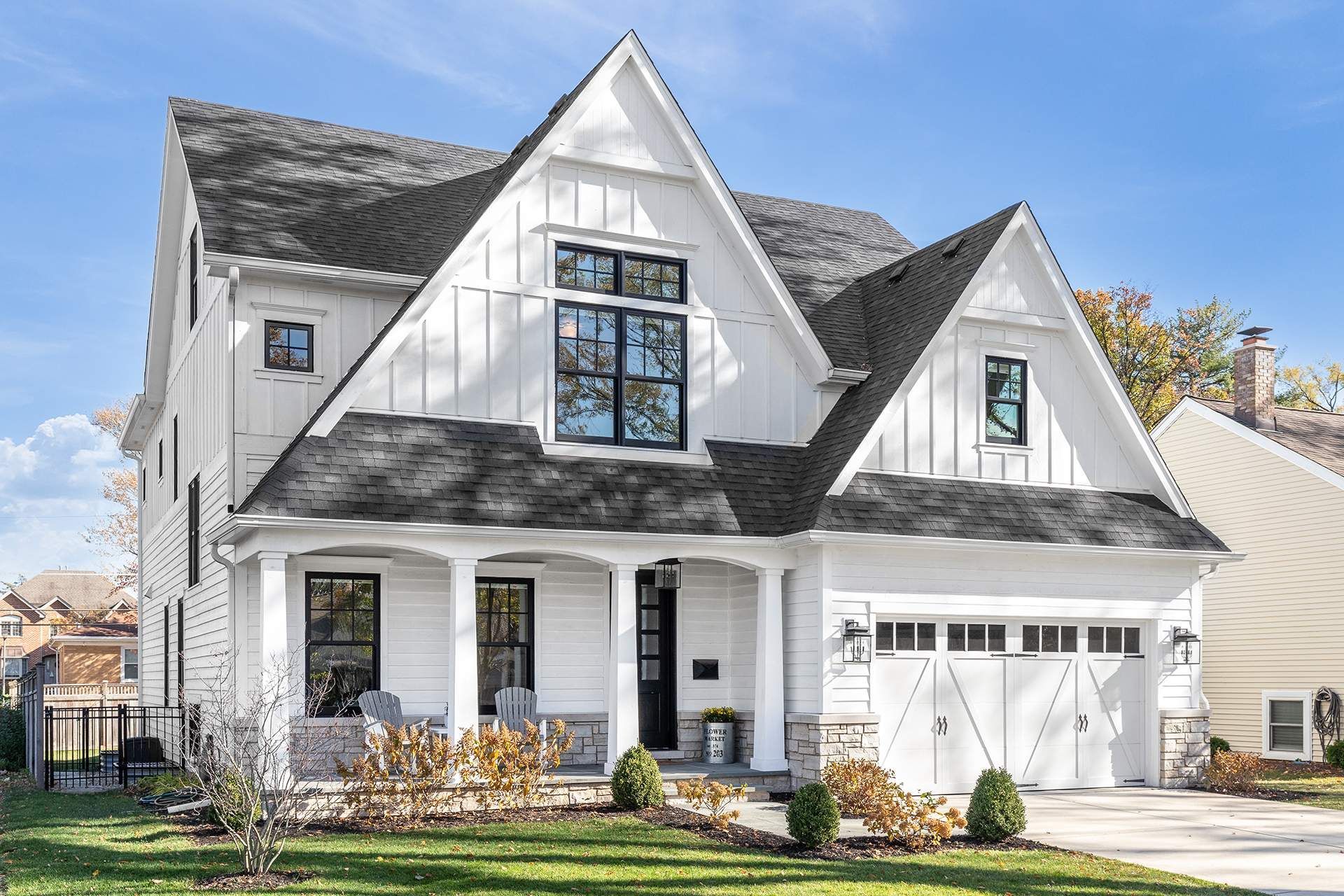 A large white house with a black roof and a porch.