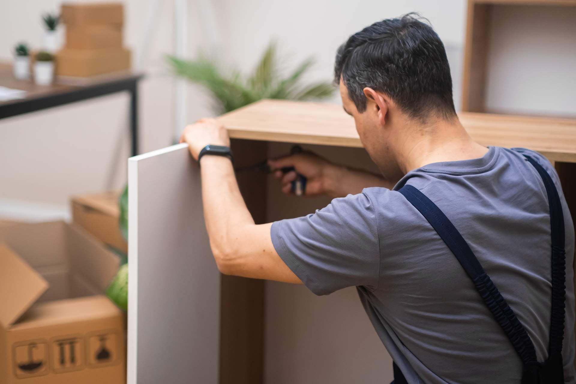 A man is fixing a cabinet with a screwdriver.