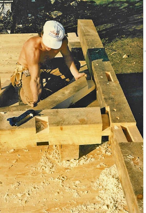 A shirtless man is working on a wooden structure