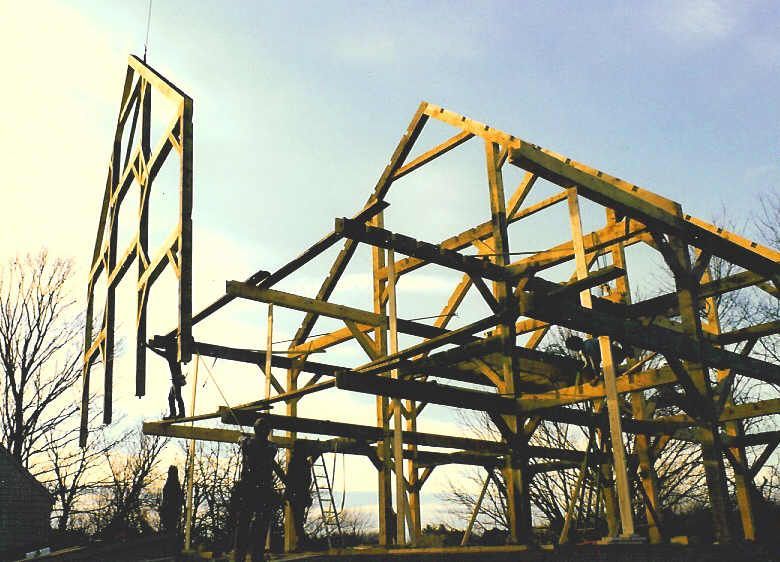 A large wooden structure is being built with trees in the background