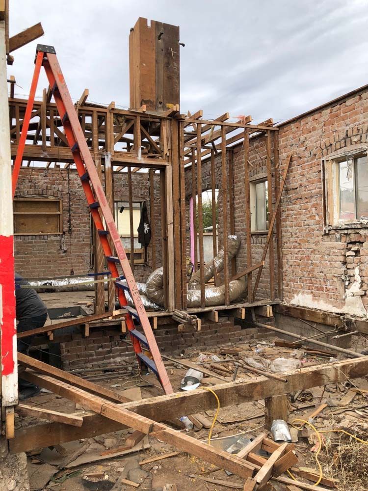A ladder is sitting in front of a brick building under construction.