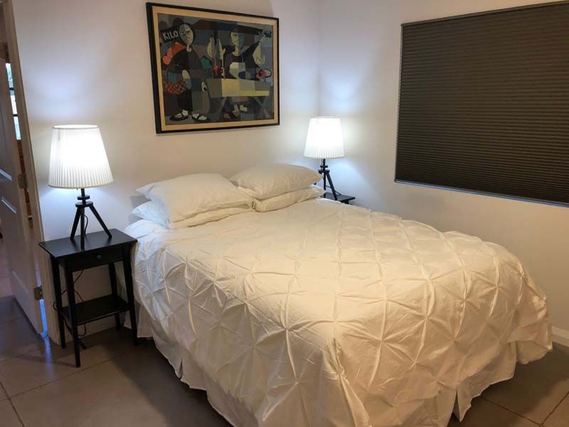 A bedroom with a bed , two lamps and a painting on the wall.