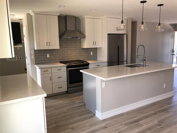 A kitchen with white cabinets , stainless steel appliances , and a large island.