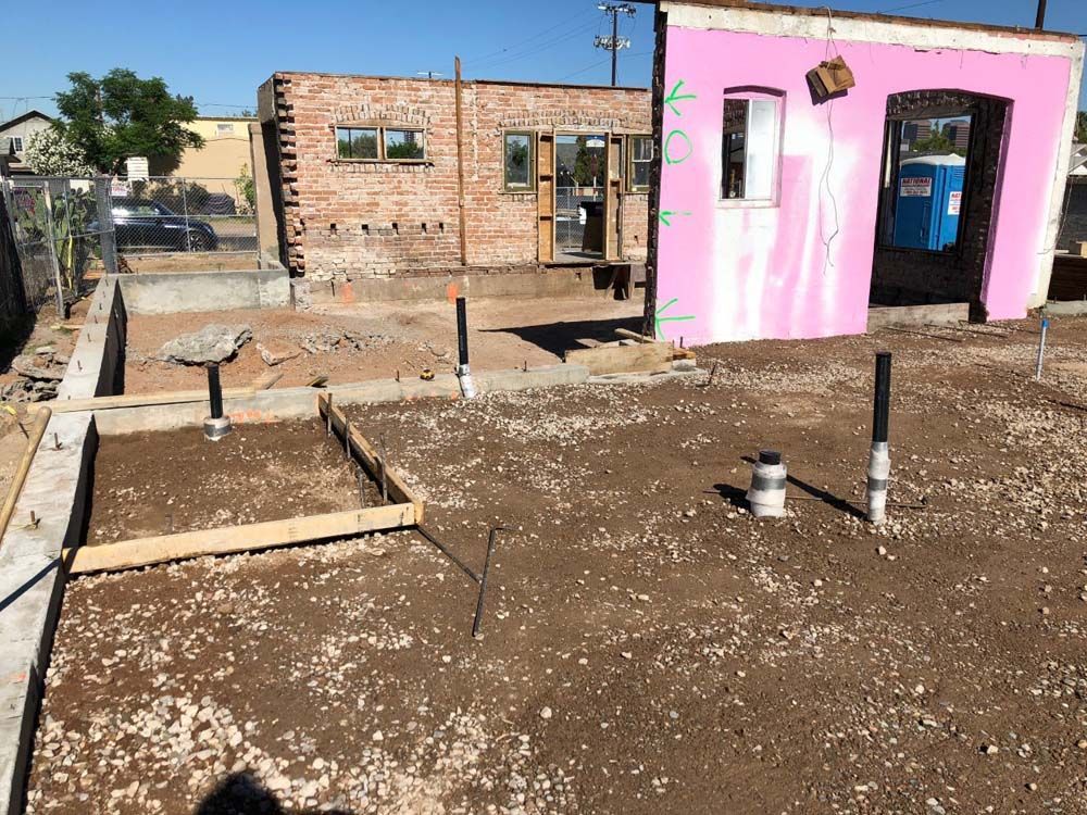 A pink building is being built next to a brick building.