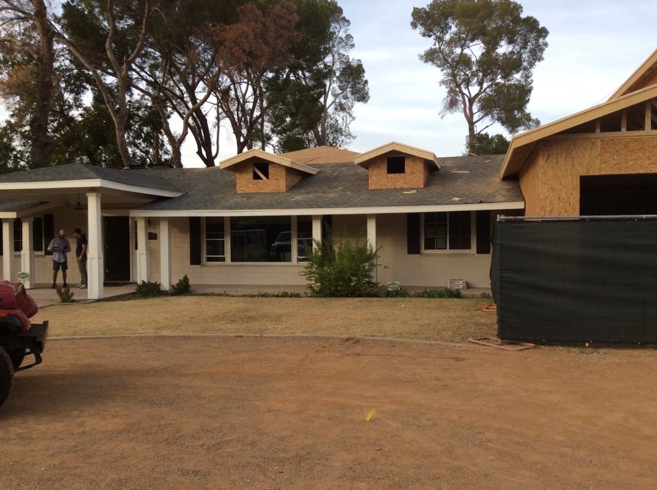 House undergoing renovation with exposed framing; beige and brown tones.