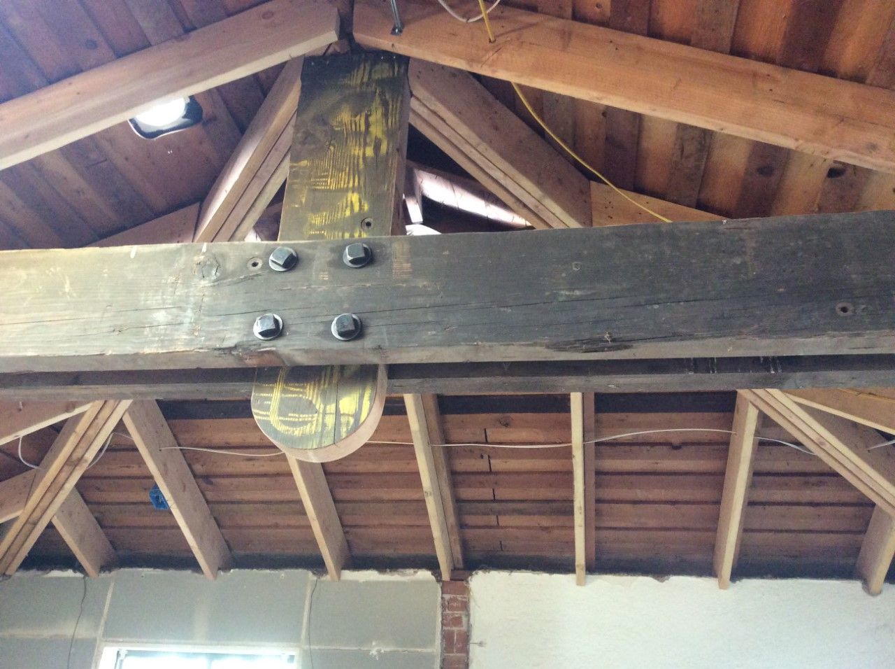 A wooden beam is hanging from the ceiling of a building