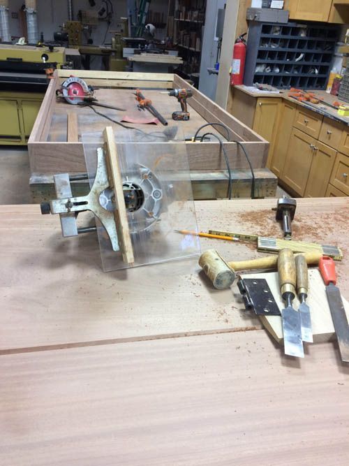 A wooden table with tools and a router on it in a workshop.