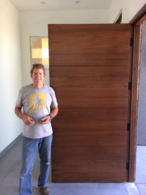 A man is standing in front of a large wooden door.