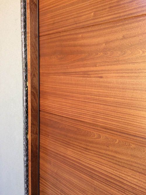A close up of a wooden door with a white wall in the background.