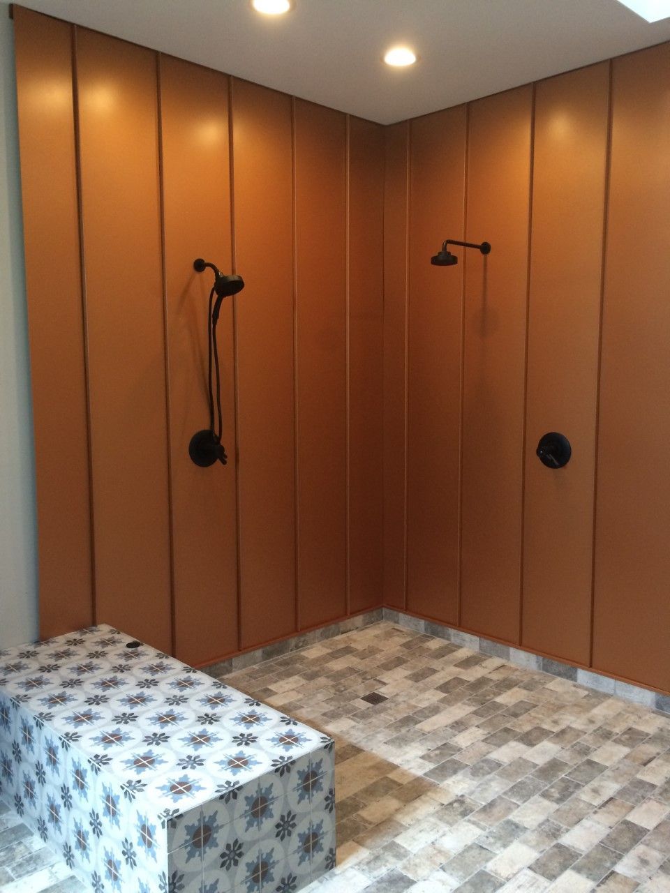 A bathroom with two showers and a bench.