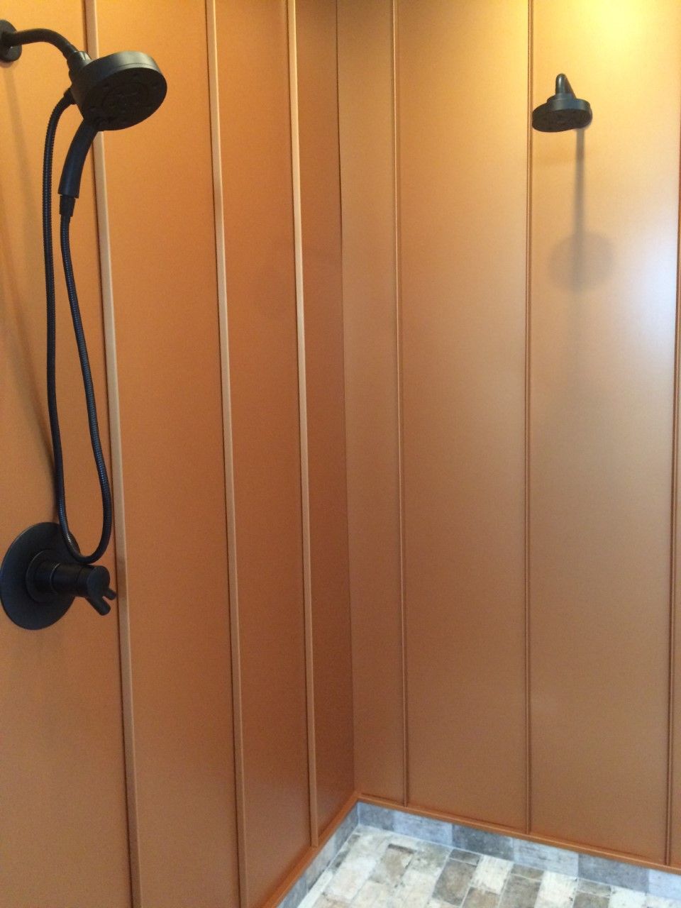 A shower with two shower heads and a tiled floor