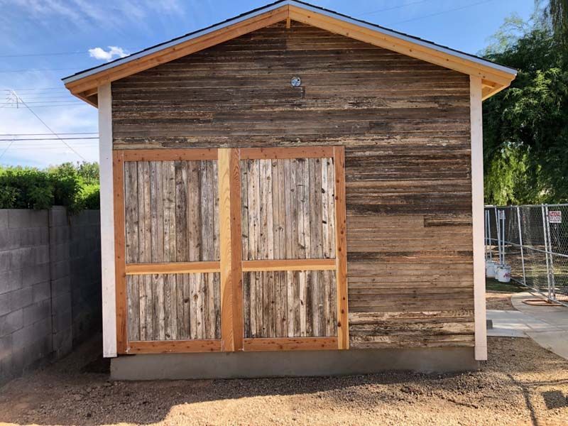 A small wooden shed with a roof is sitting in the dirt.