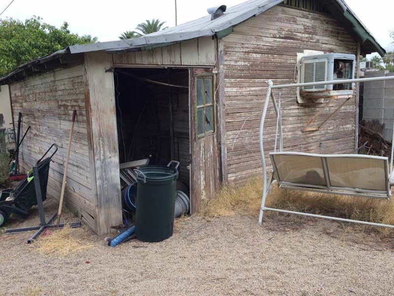 A wooden shed with a swing in front of it.