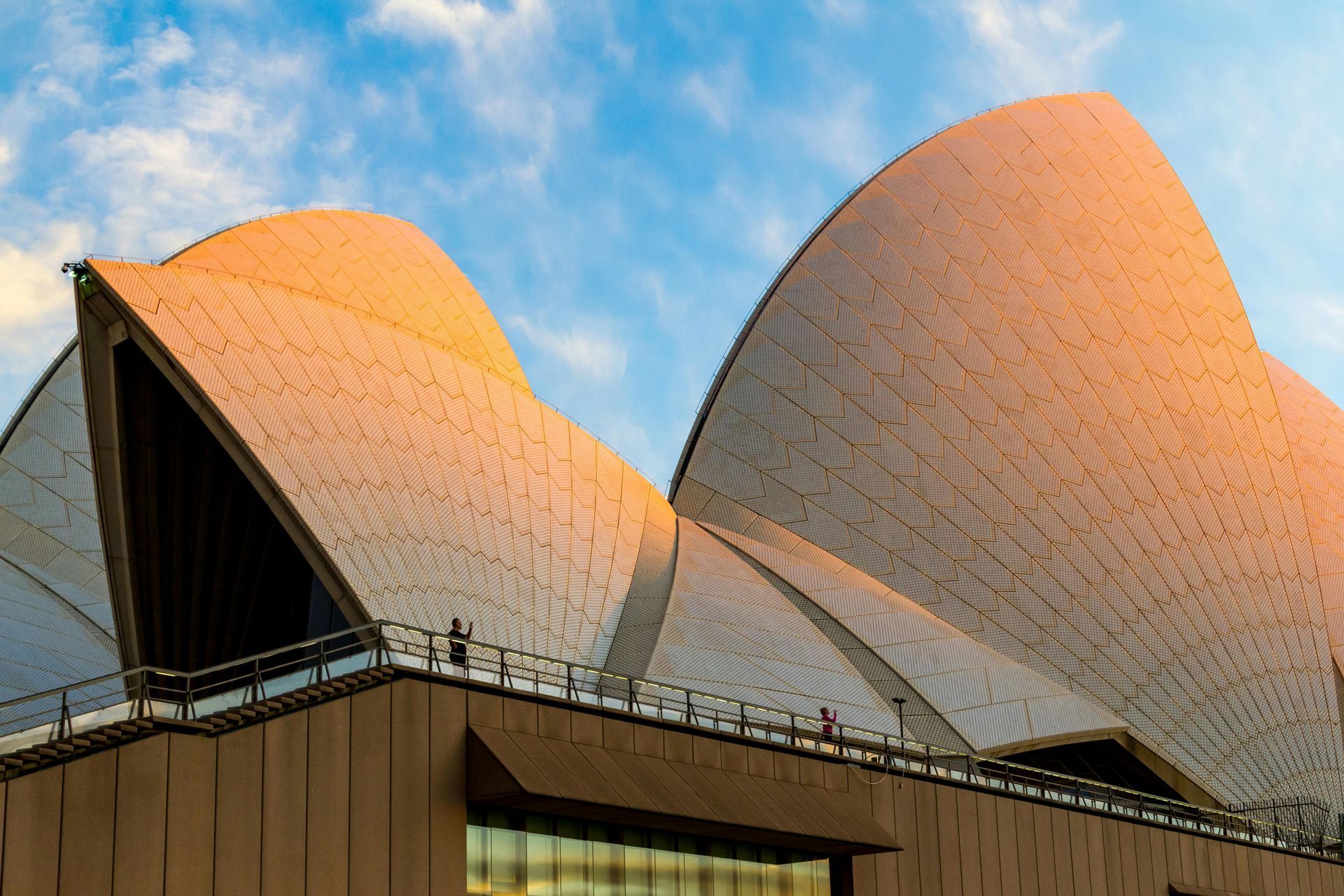 Sydney Opera House, a modern architectural landmark with white, shell-like sails against a blue sky.